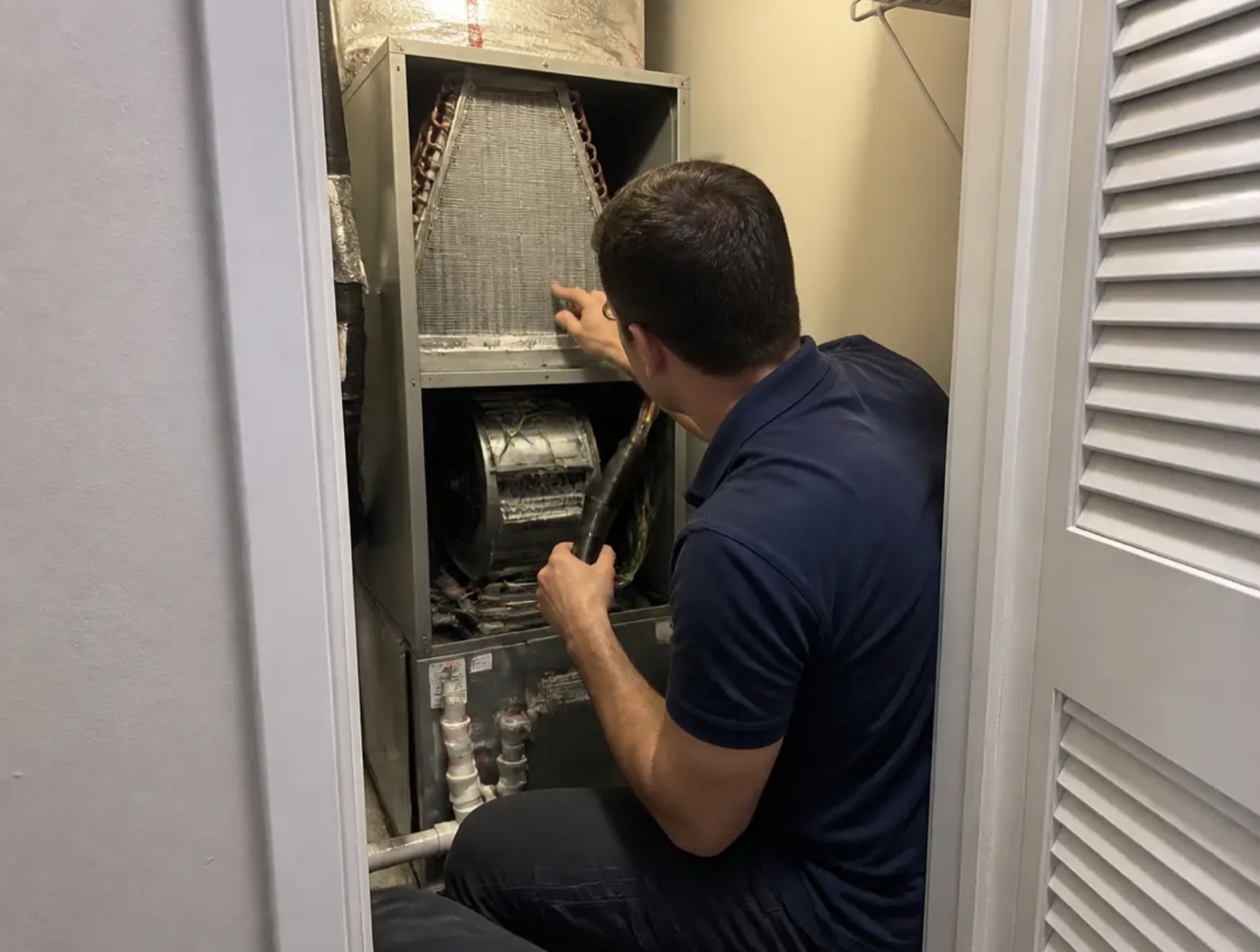 Open indoor air handler showing the coil and blower where musty odors start