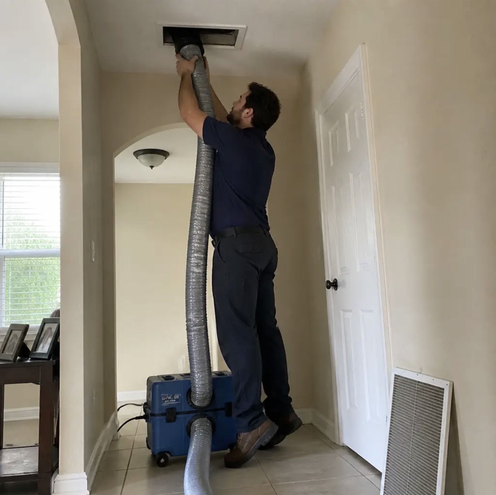Technician cleaning a home air duct with a vacuum